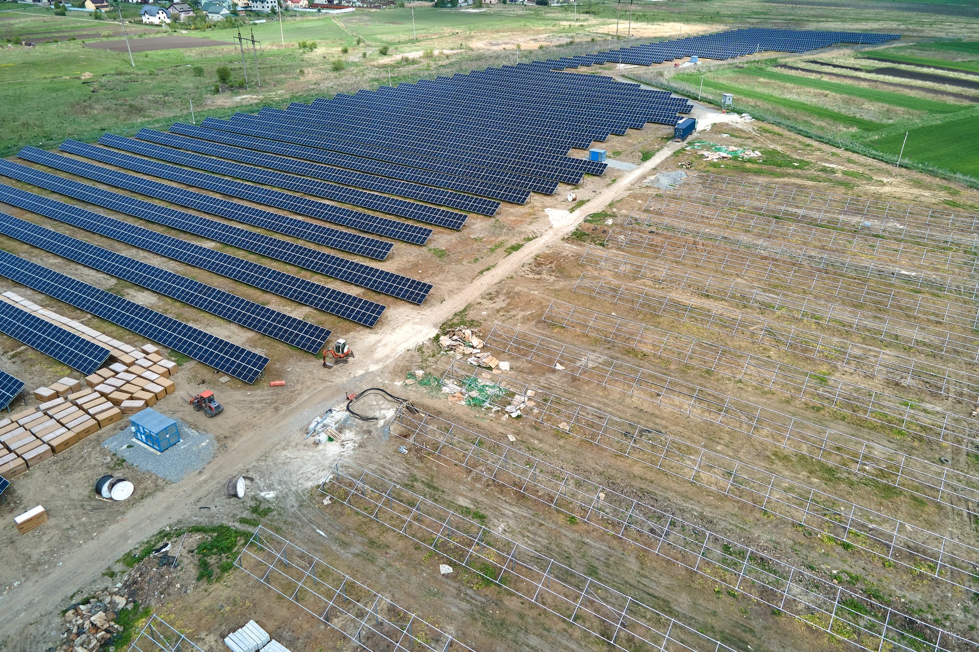 Aerial view of big electric power plant under construction with many rows of solar panels on metal frame for producing clean electrical energy. Development of renewable electricity sources